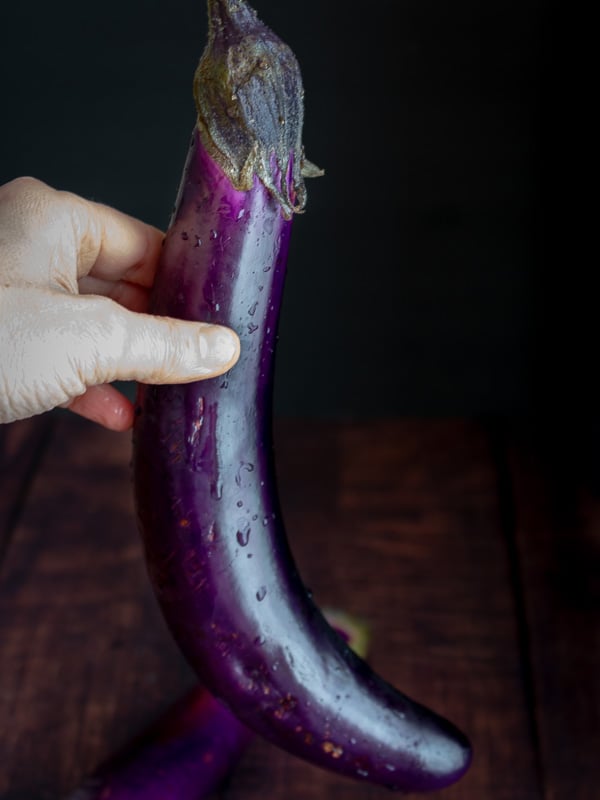 Long Asian eggplant being held.