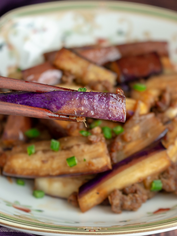 Chinese Eggplant with Spicy Pork being held with chopsticks.