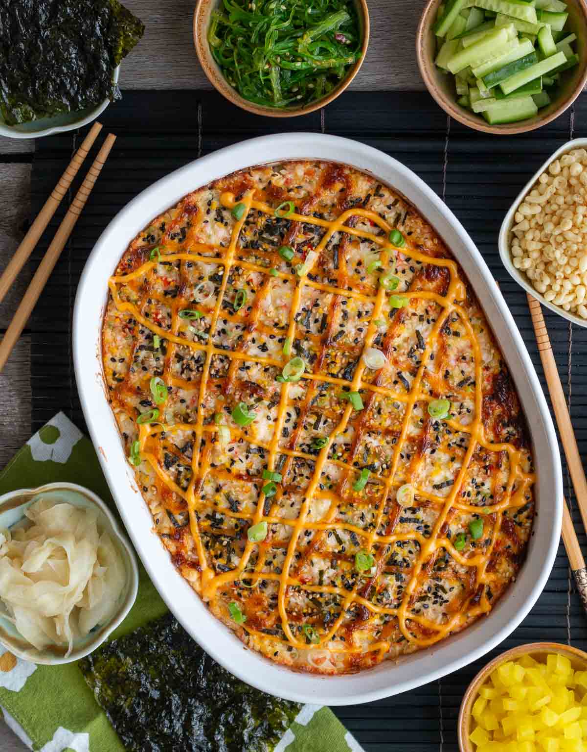 Top down shot of a fresh out of the oven hot California roll casserole surrounded by all the fun toppings. 