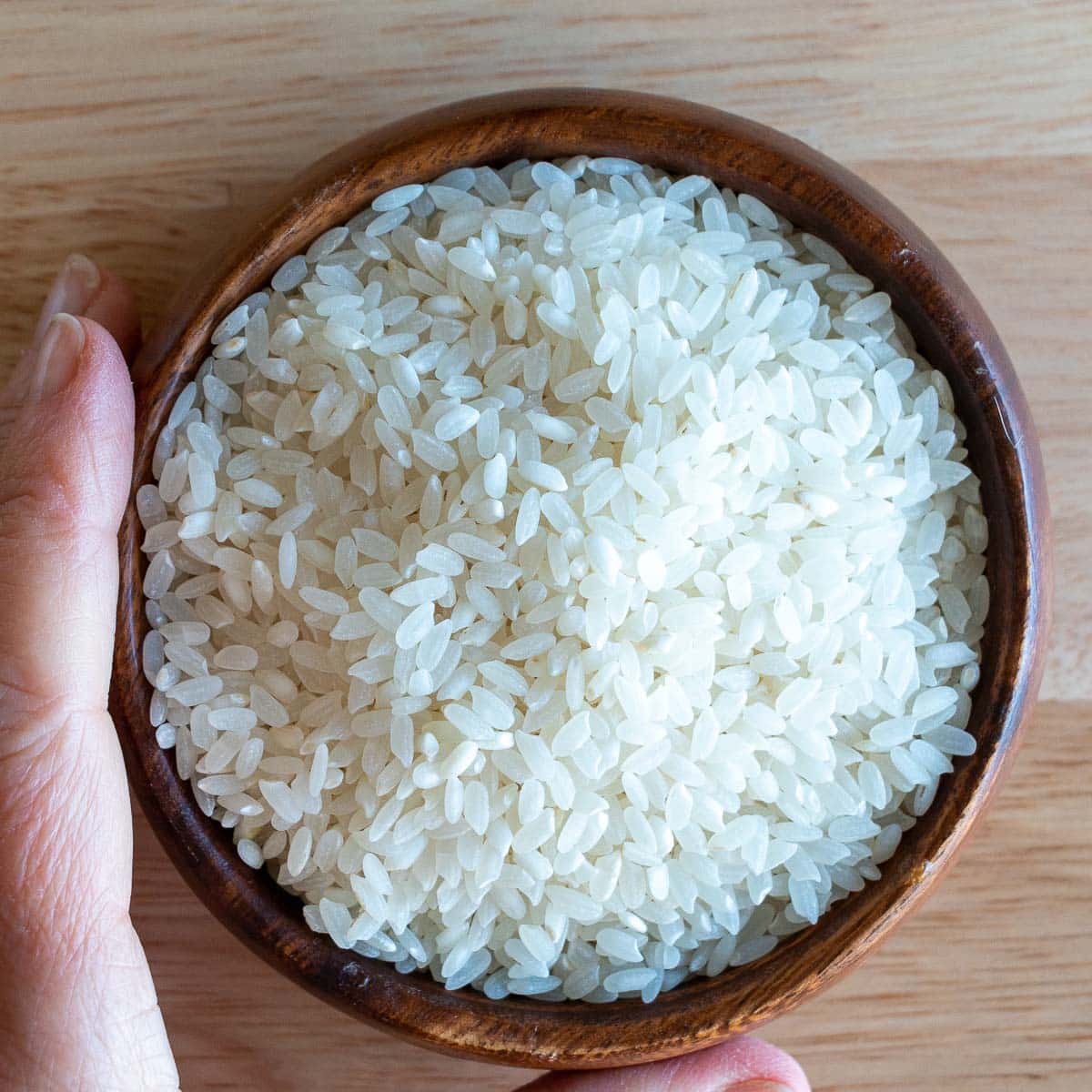 Uncooked Japanese short grained sushi rice in a wooden bowl.