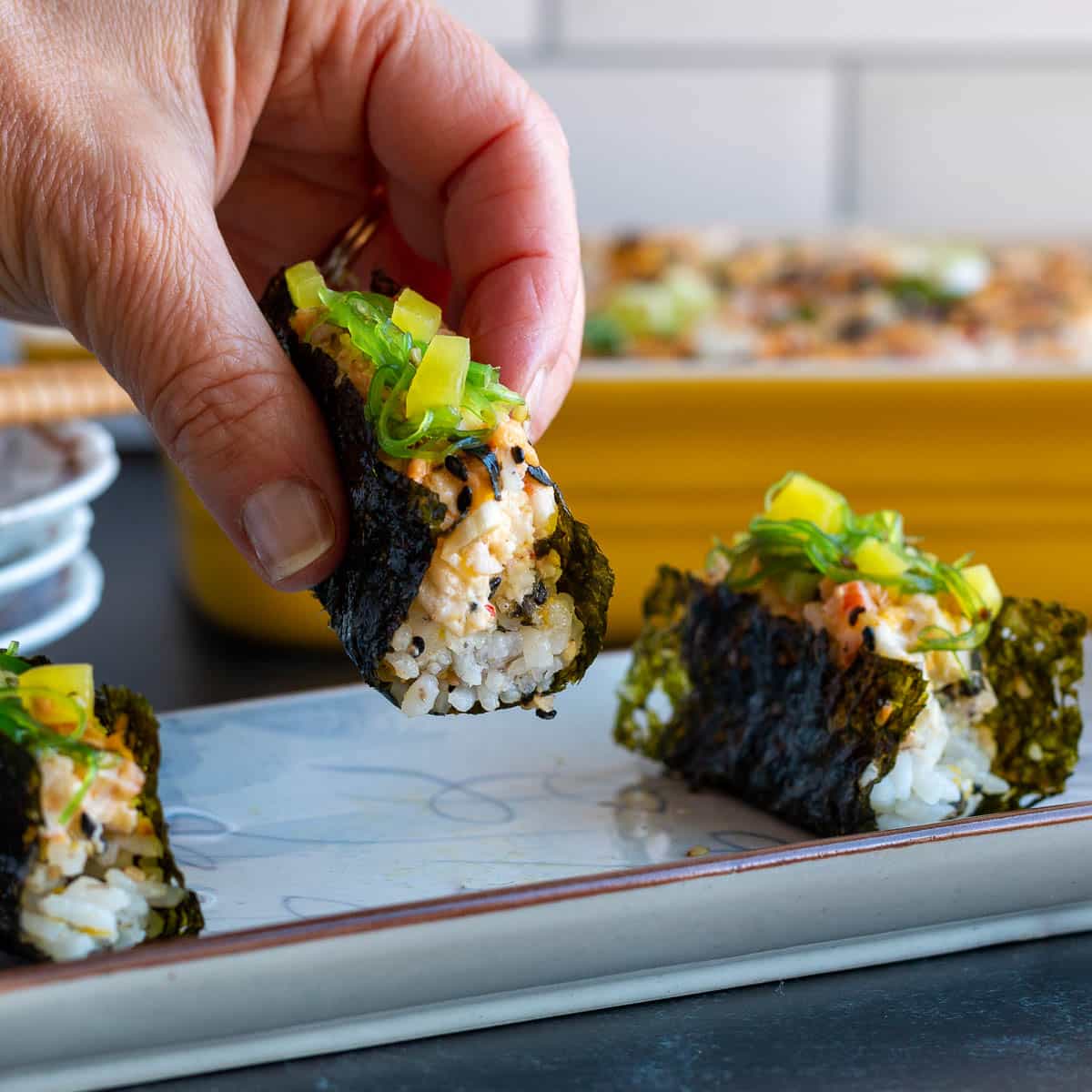 Holding a prepared Korean snack nori with a dollop of hot sushi bake. 