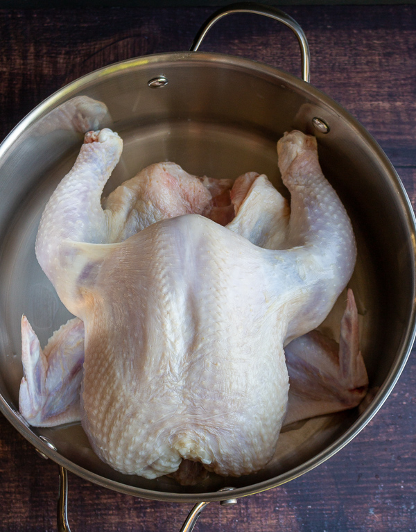 Raw chicken that has just been washed thoroughly and patted dry in a pot. 