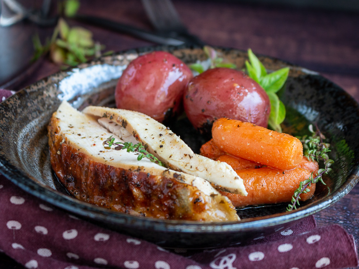 Plate of sliced chicken, potatoes and carrots served on a black plate. 