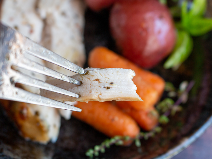 Bite shot of a perfectly tender and moist slice of chicken breast. 