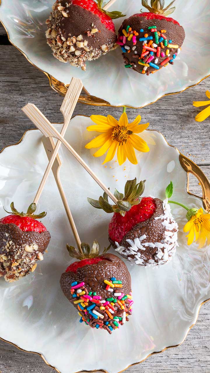 Decorated chocolate covered frozen strawberries on a white plate.