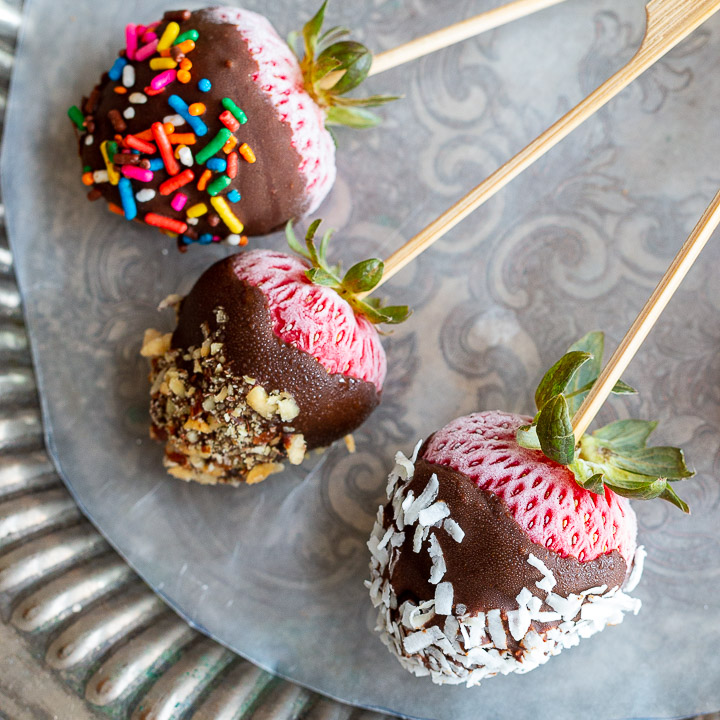 frozen strawberries decorated with coconut, crushed nuts and sprinkles.