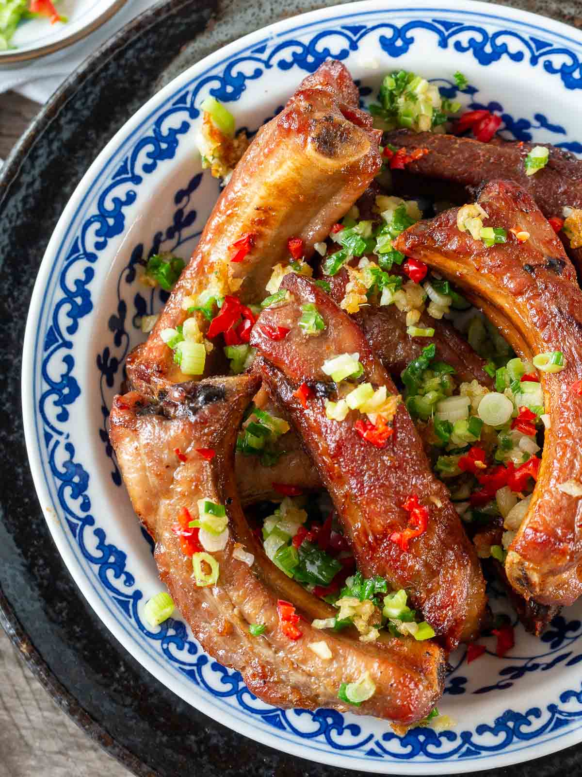 Top Down photo of air fryer ribs perfectly golden brown and topped with fried garlic and chilis.