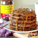 Gluten free coffee pancakes drizzled with maple coffee syrup on a white plate with a cup of coffee.