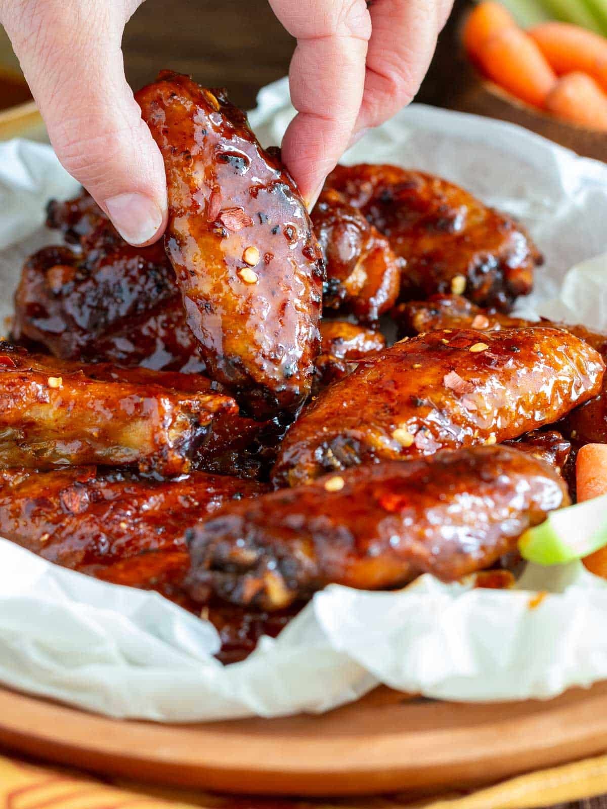 Grabbing a sticky and crispy hot honey wing off a plate lined with parchment paper. 