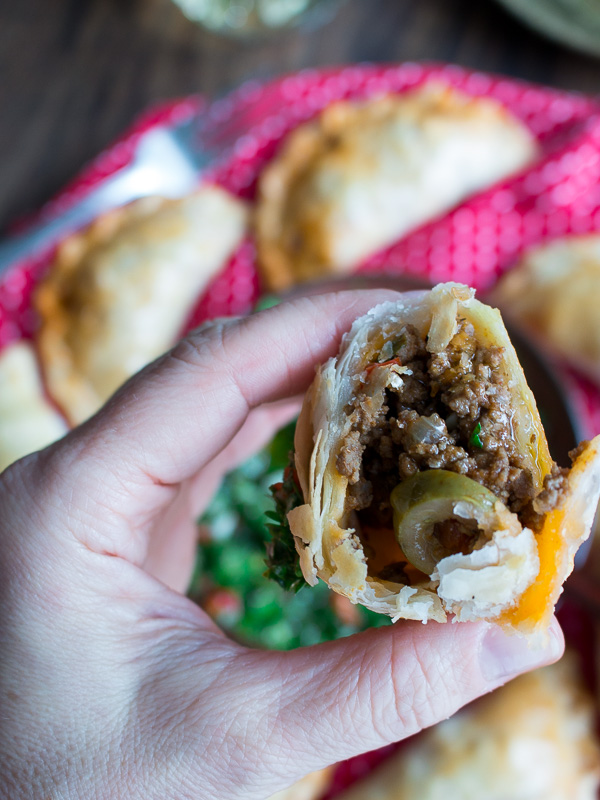 The bite shot showing ground beef, olives and flaky crust.