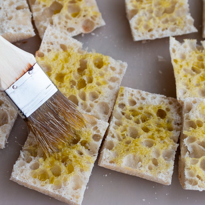 Italian bread getting brushed with EVOO.