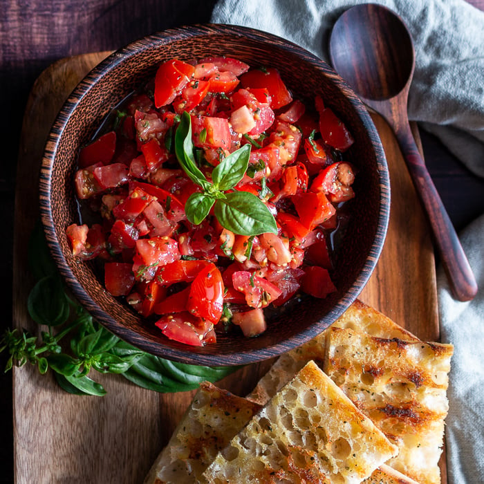 Grilled Italian bread with delicious tomatoes with EVOO and aged balsamic on a wooden platter.