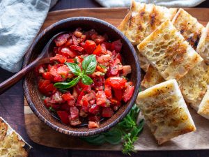 Grilled Italian bread with delicious tomatoes with EVOO and aged balsamic on a wooden platter.