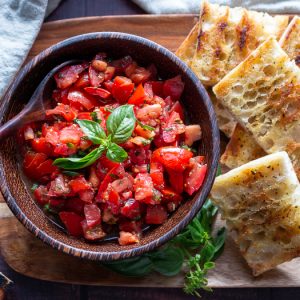 Grilled Italian bread with delicious tomatoes with EVOO and aged balsamic on a wooden platter.