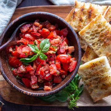 Grilled Italian bread with delicious tomatoes with EVOO and aged balsamic on a wooden platter.