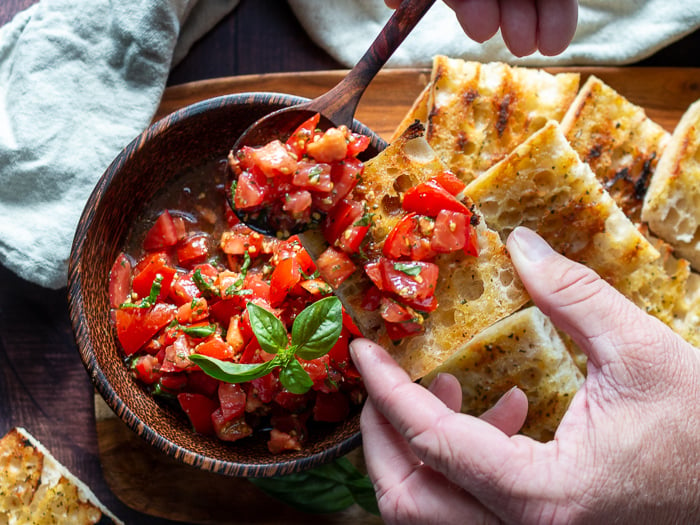 Scooping delicious marinated tomatoes with EVOO and Balsamic onto of crusty grilled bread. 