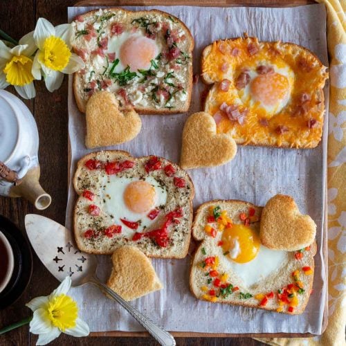 4 different baked eggs in toast with different toppings.