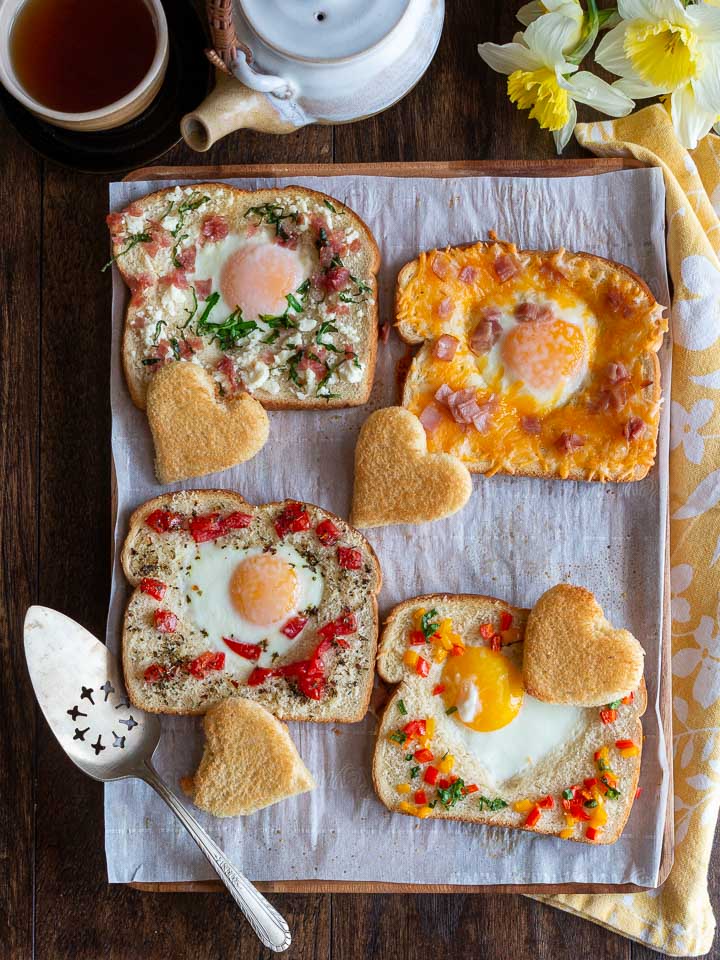 4 different topped eggs in toast baked with a side of tea.