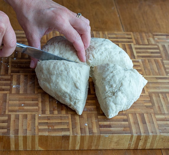 Cutting dough into 4 sections with a butter knife.