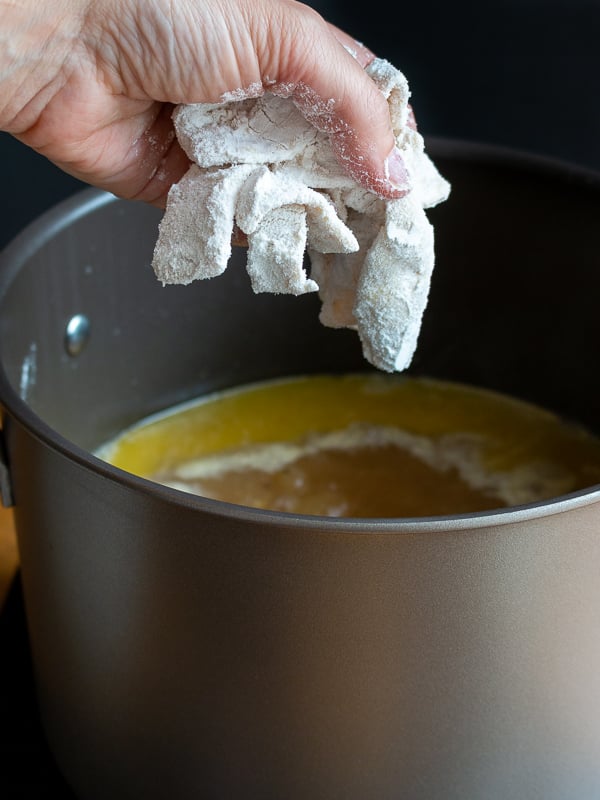 Putting a handful of noodles into the boiling broth.