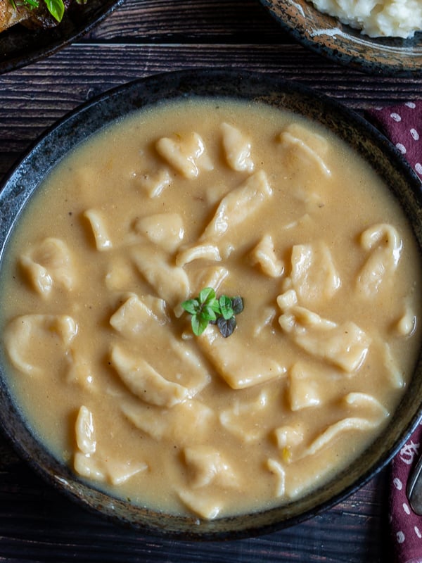 Top down photo with a cooked bowl of Grandma's Chicken and Sliders in a black bowl. Garnished with green herbs.