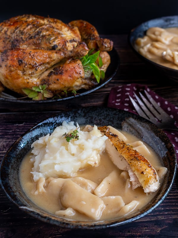 Grandma's Chicken and sliders served in a black plate with mashed potatoes and roasted chicken. 