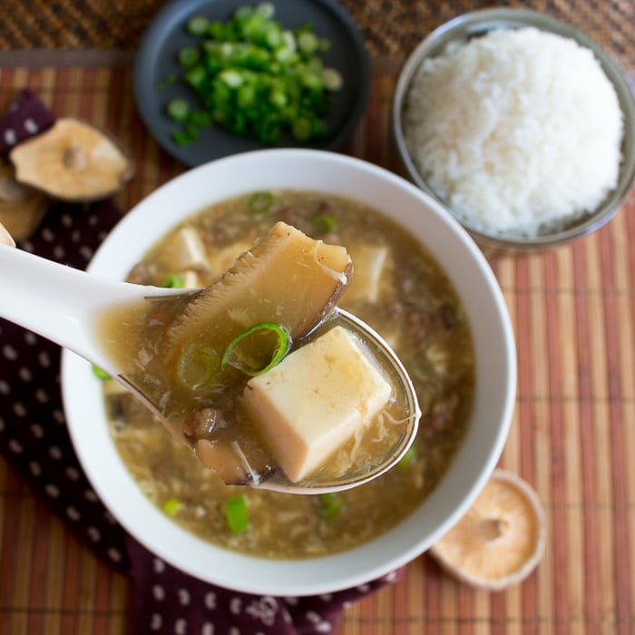 Hot and Sour Soup in a spoon with a side of rice.