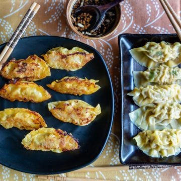Plate of pan fried and boiled Chinese dumplings on black plates.