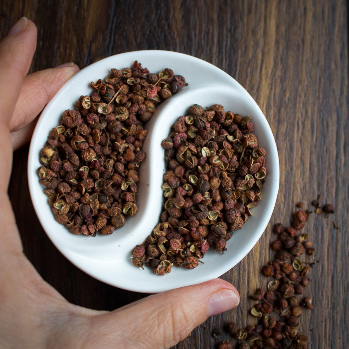 Dried Sichuan peppercorns in a white yin and yang bowl.