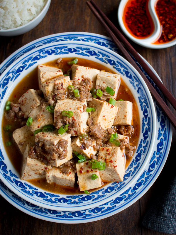 Close up of mapo tofu really showing the chili spices and little bits of pork and green onions. 