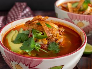 Tortilla soup topped with crispy tortillas and cilantro.