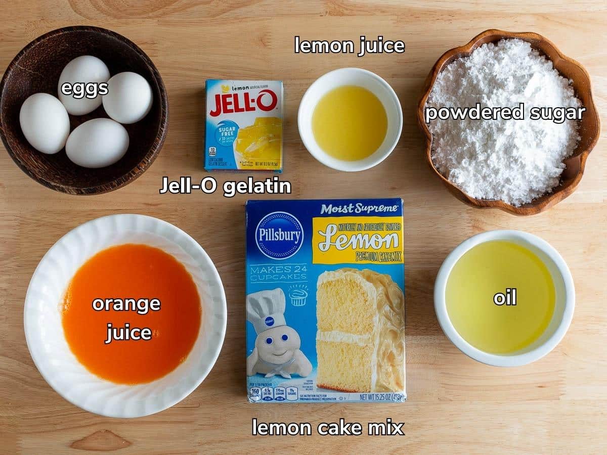 Ingredients to make a lemon poke cake with a lemon glaze is laid out on a wooden table. 