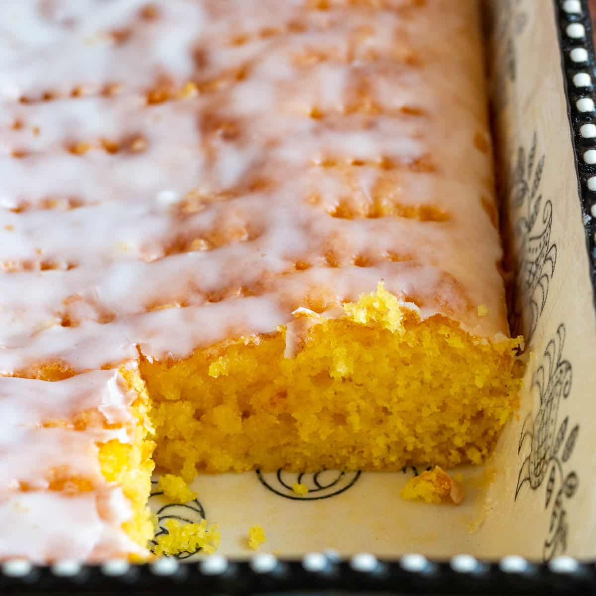 One slice cut out of the sheet pan with jello lemon poke cake.