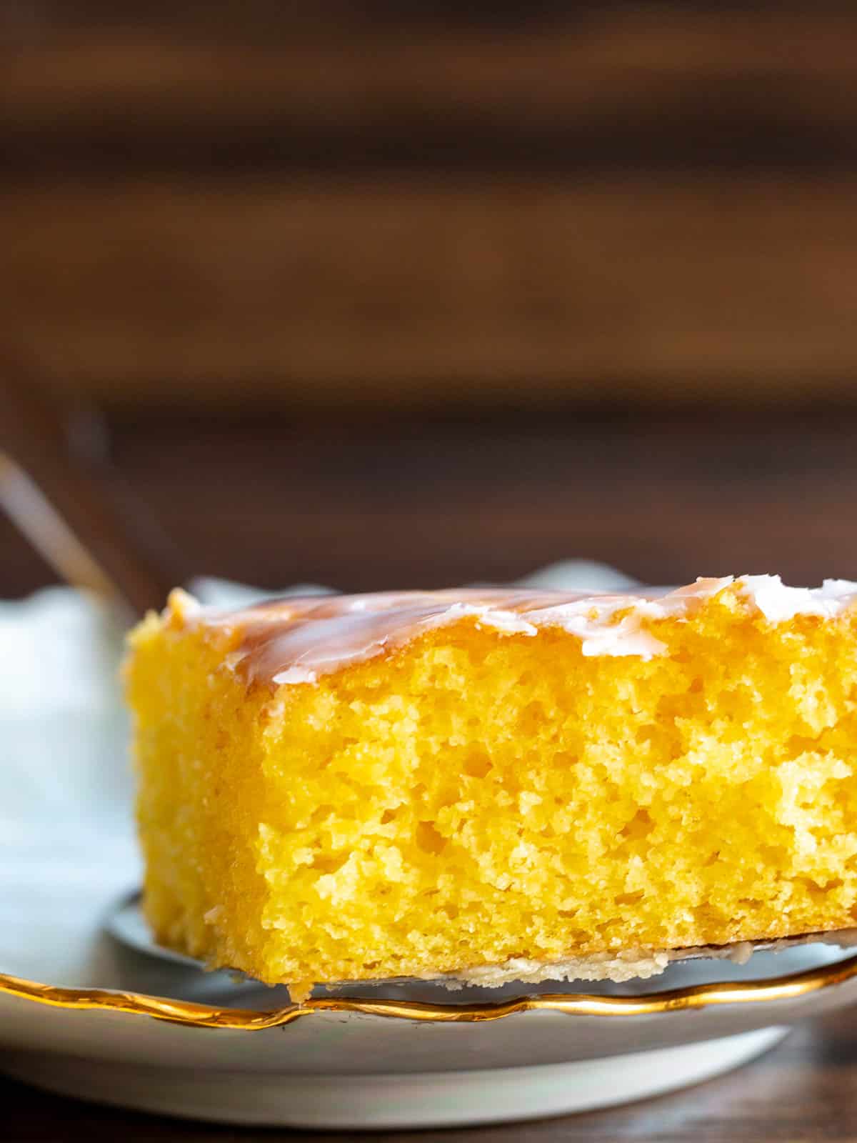 Placing a single slice of jello poke cake on a white plate with a serving spatula.