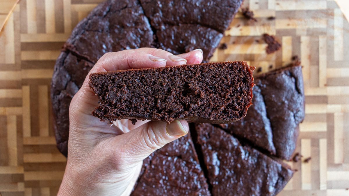Holding a brownie in our hands to show the fudgy thick brownie texture.