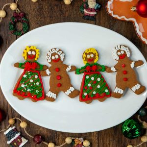 4 adorable gingerbread men and women on a white plate all holding hands.