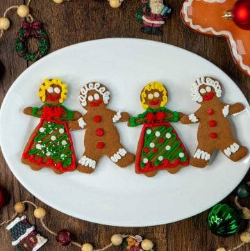 4 adorable gingerbread men and women on a white plate all holding hands.