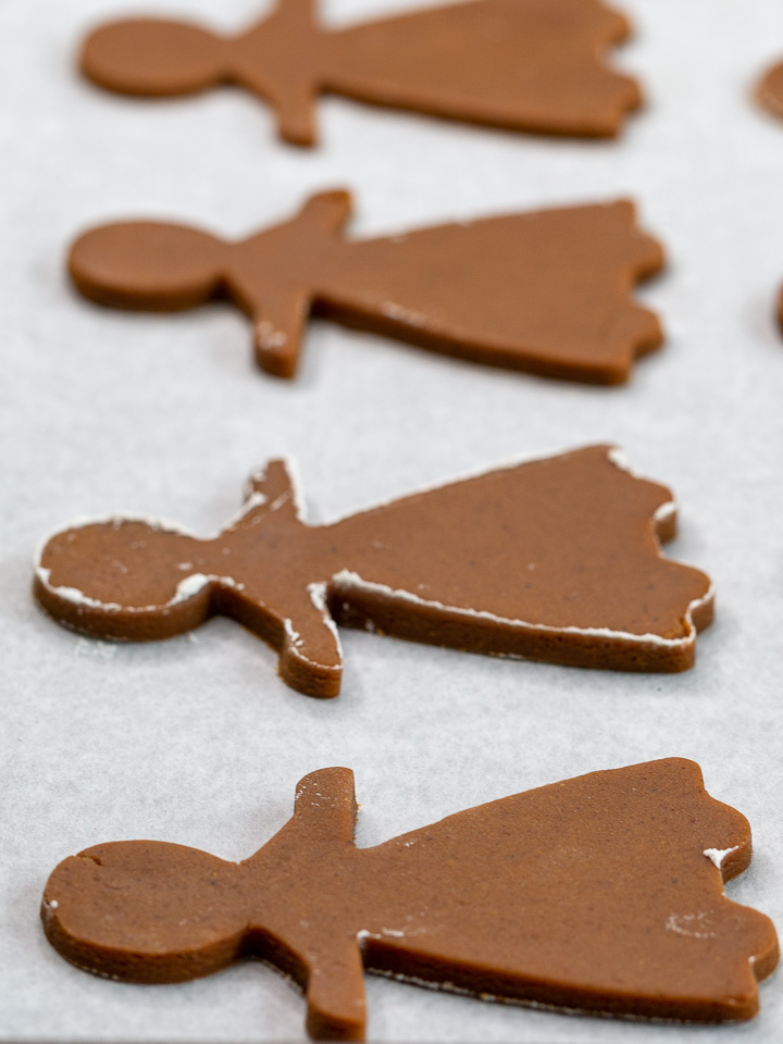 4 gingerbread women on lined baking sheet with parment paper ready to be baked. 