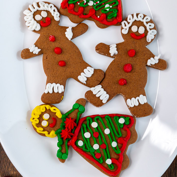 4 cute little decorated homemade gingerbread cookies on a plate. 