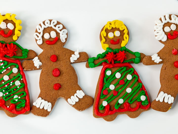 4 decorated cut out molasses cookies holding hands.