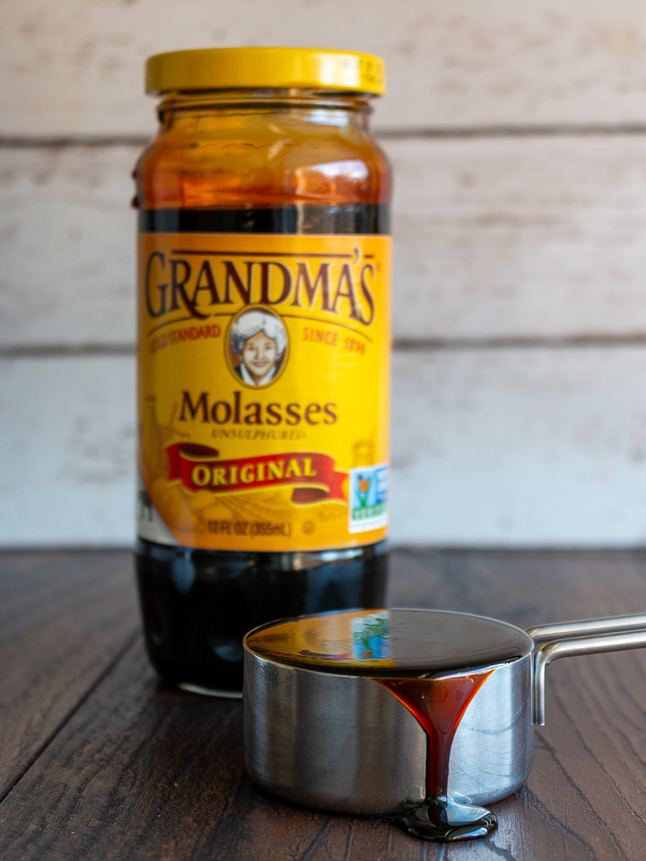 Grandma's original molasses in a jar and a cup overflowing with molasses.