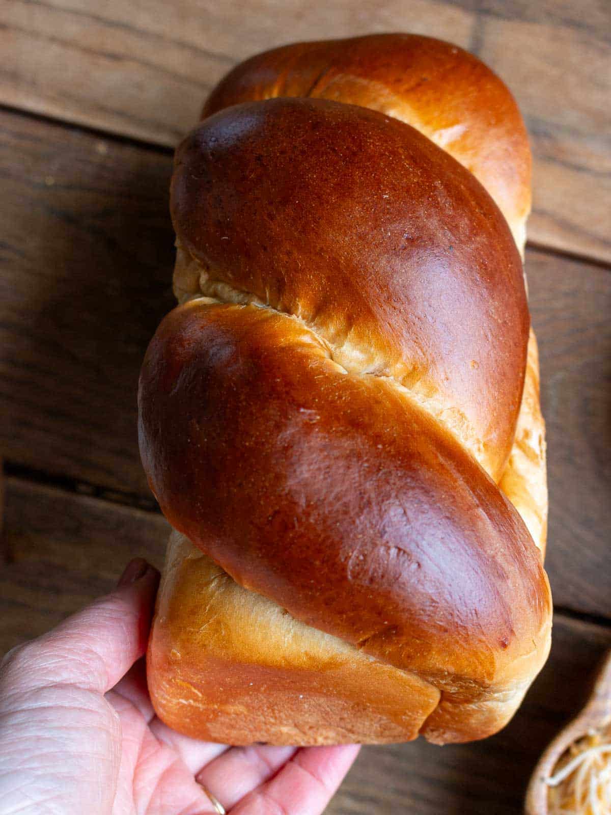 Holding a whole loaf of golden brioche bread. 