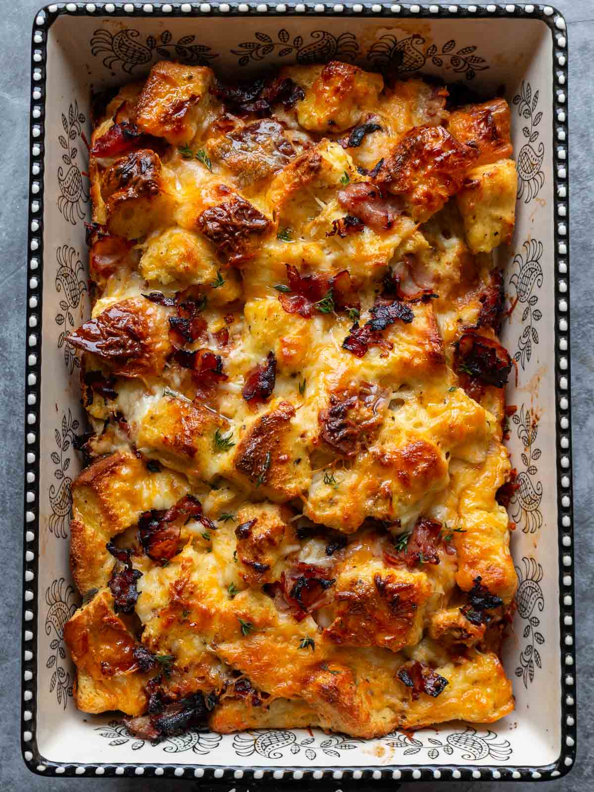 Freshly baked savory breakfast bread pudding hot out of the oven and topped with fresh thyme. 