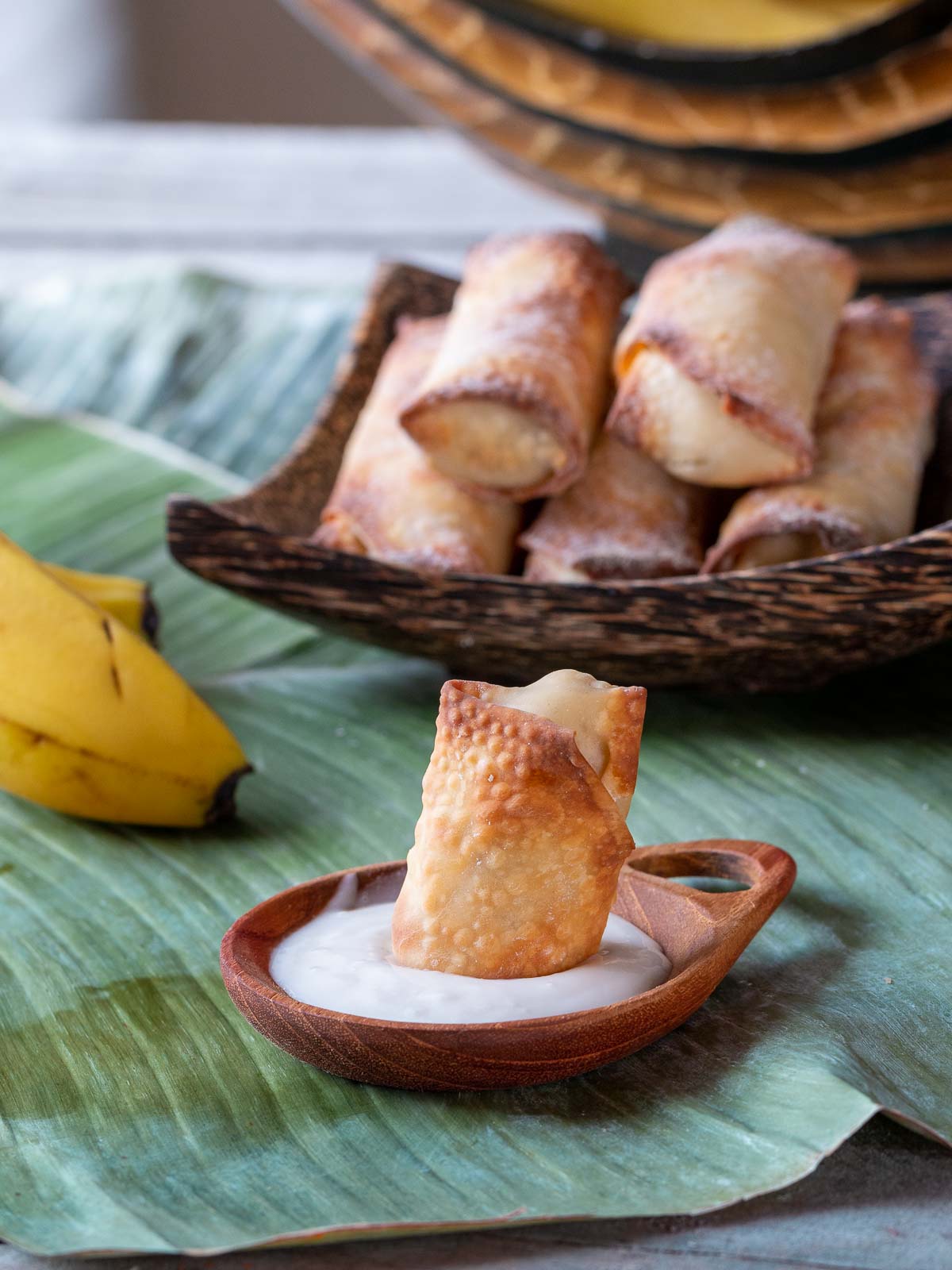 Banana Spring roll getting dipped in coconut whipped cream.