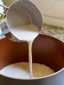 Adding coconut milk to the washed sticky rice.