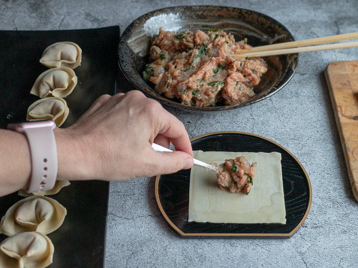 Placing a heaping teaspoon of the filing in the center of the wonton wrapper.