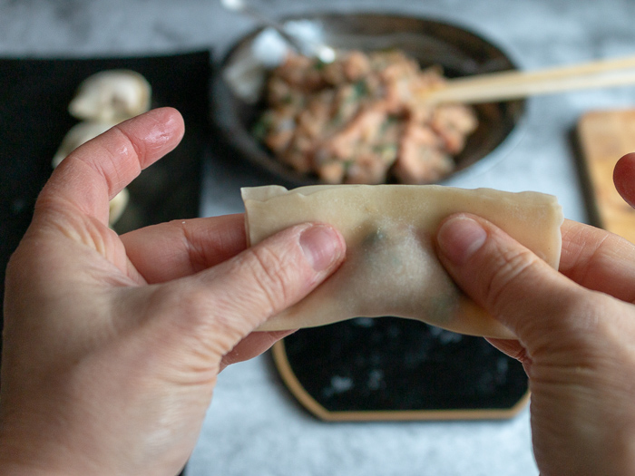 Folding the wonton in half and getting the air out around the filling.