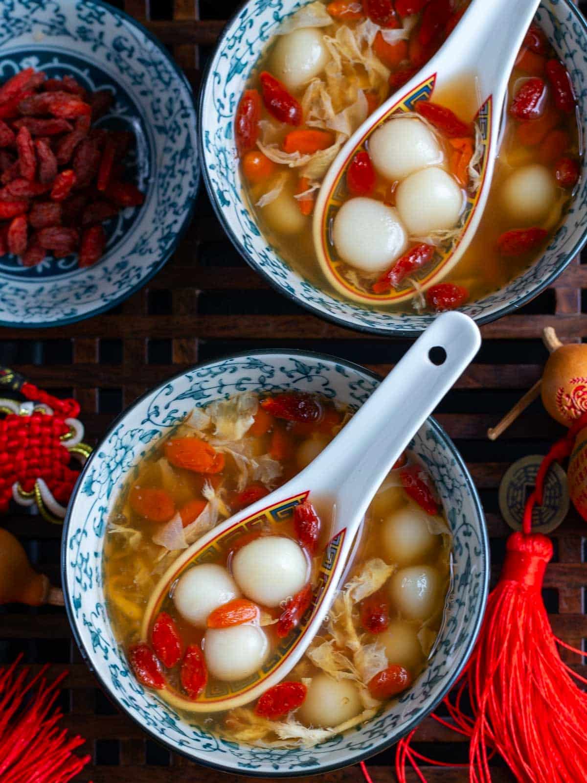 2 bowls of glutinous rice balls in osmanthus sweet soup in blue Chinese bowls with CNY decorations.