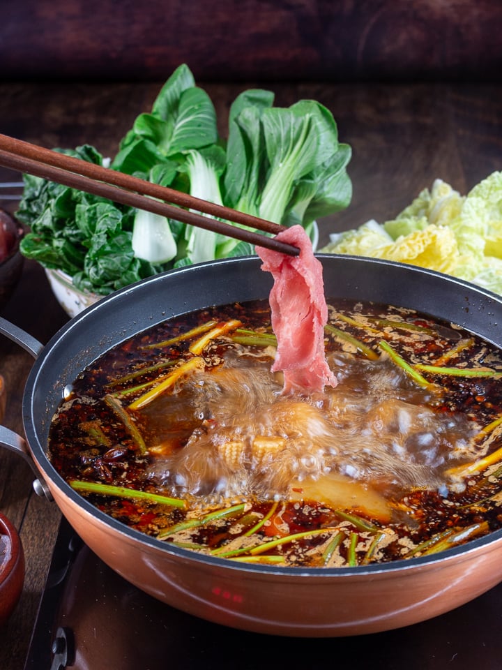 Thin beef slices getting dipped into the Spicy Sichuan Hot Pot broth.