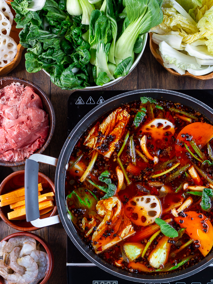 Beef, green leafy vegetables and squash around a bubbling Spicy Sichuan Hot pot.